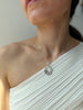 Close-up of a person wearing a delicate silver necklace with a hummingbird detail.