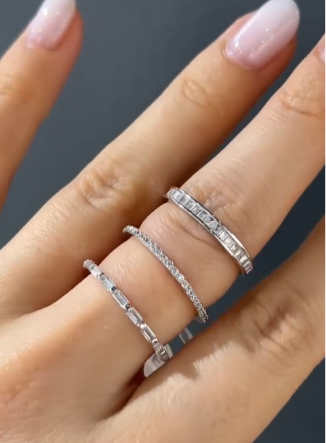 Three rings with white stones on a model hand.