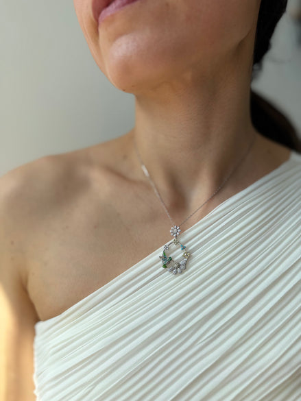 Close-up of a person wearing a delicate silver necklace with a hummingbird detail.
