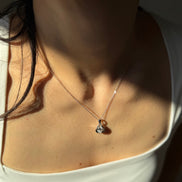 Close-up of a person wearing a delicate necklace with a small pendant.