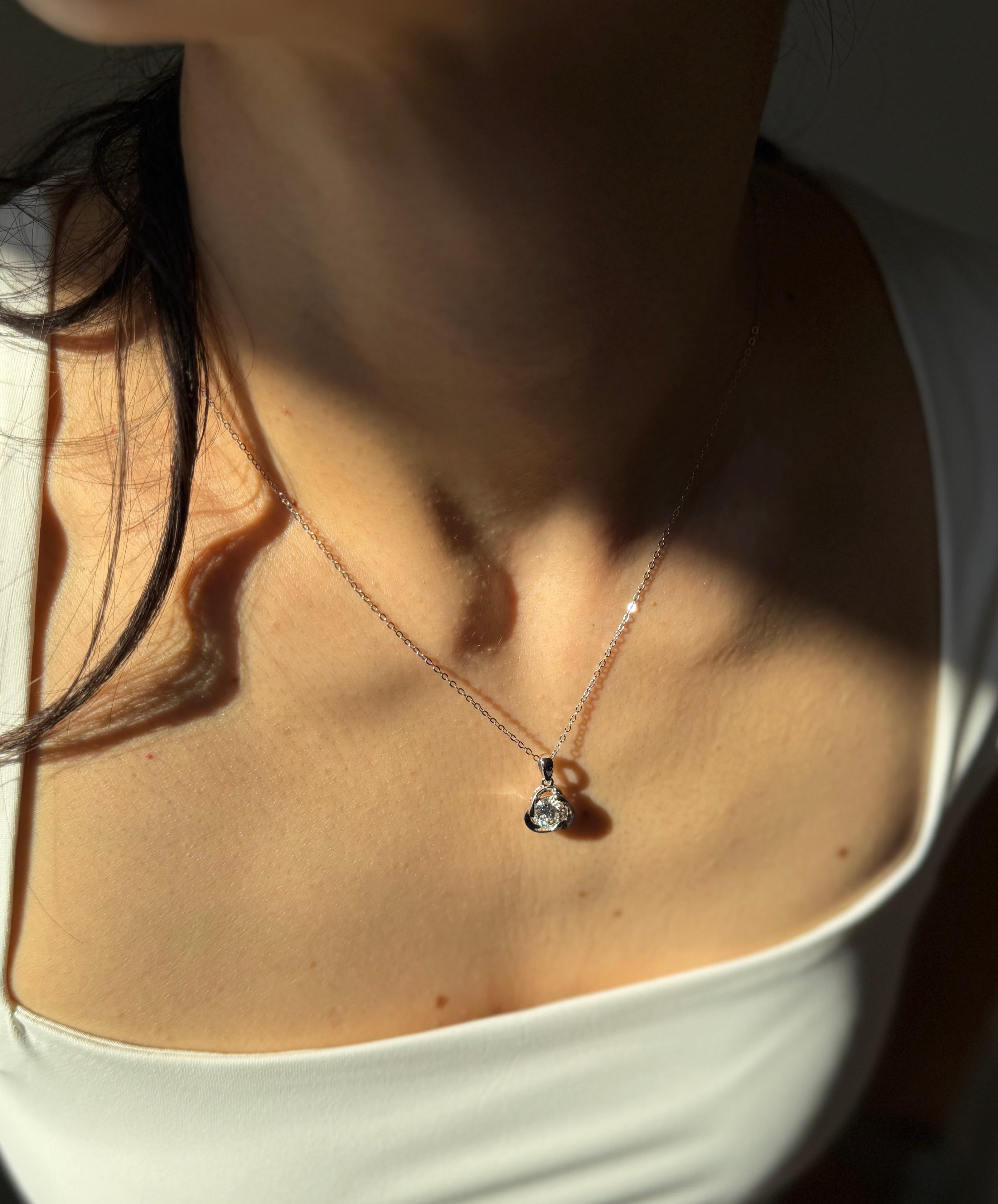 Close-up of a person wearing a delicate necklace with a small pendant.