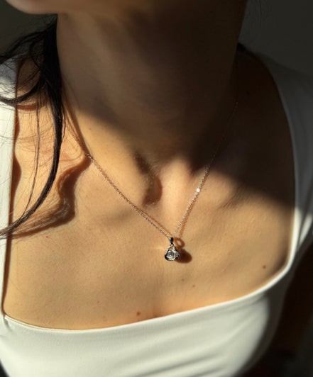 Close-up of a person wearing a delicate necklace with a small pendant.