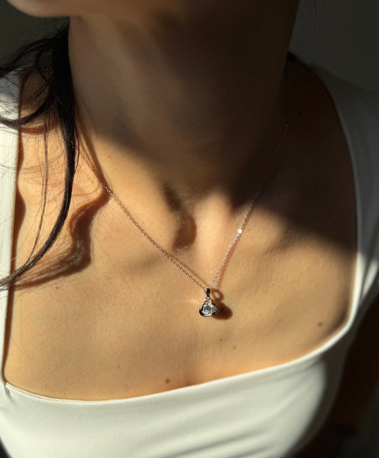 Close-up of a person wearing a delicate necklace with a small pendant.